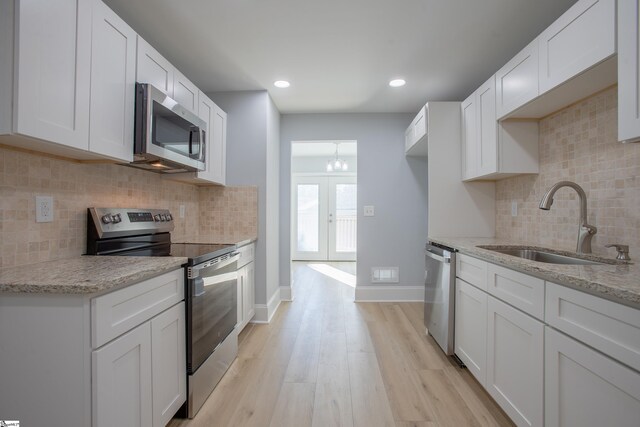 kitchen with light stone countertops, sink, white cabinets, and stainless steel appliances