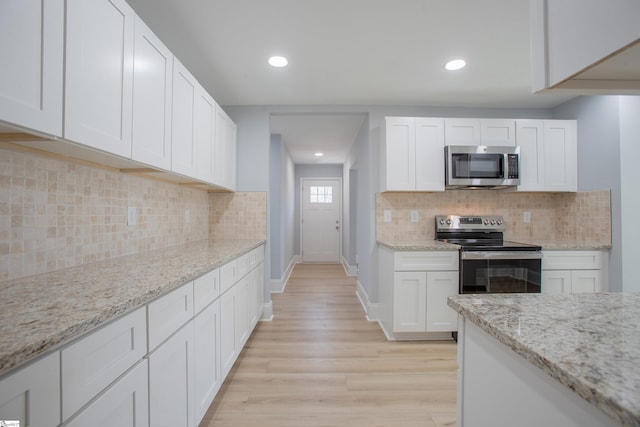 kitchen with decorative backsplash, appliances with stainless steel finishes, light hardwood / wood-style floors, light stone counters, and white cabinetry