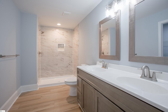 bathroom featuring a tile shower, vanity, toilet, and hardwood / wood-style floors