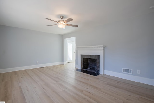 unfurnished living room featuring ceiling fan, light hardwood / wood-style flooring, and a brick fireplace