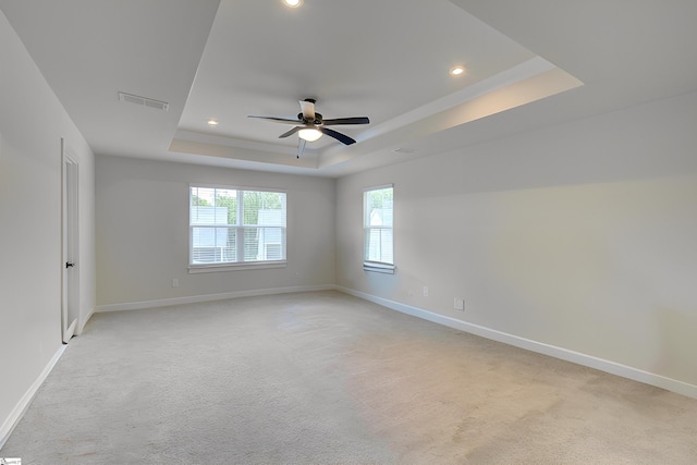 carpeted spare room with a tray ceiling and ceiling fan