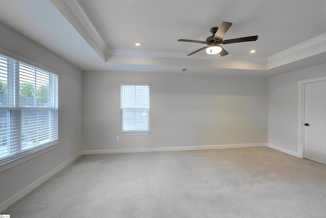 carpeted empty room with a tray ceiling, a wealth of natural light, and ceiling fan