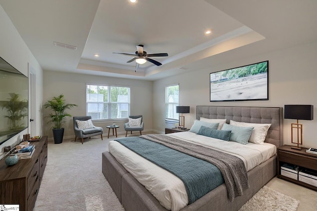 carpeted bedroom featuring ceiling fan and a tray ceiling