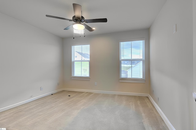 empty room with light colored carpet, a wealth of natural light, and ceiling fan