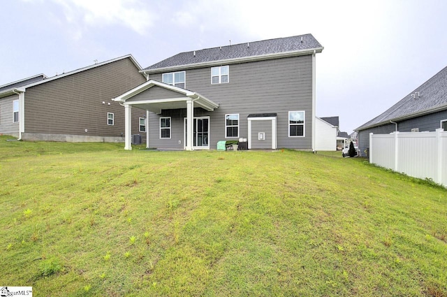 rear view of property featuring a lawn and central AC unit