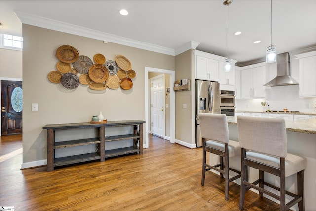 kitchen with white cabinets, light stone counters, and wall chimney exhaust hood