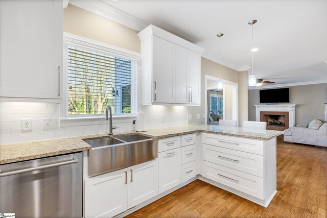 kitchen with kitchen peninsula, decorative light fixtures, stainless steel dishwasher, and white cabinetry