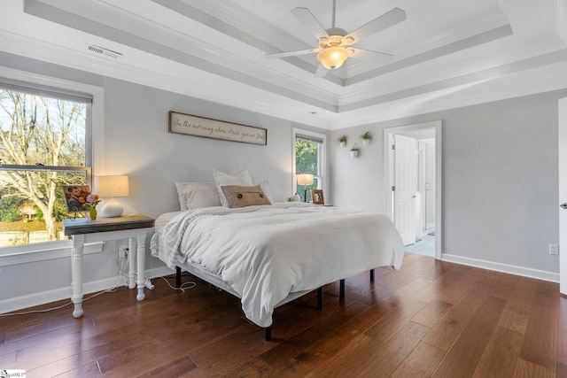 bedroom with ceiling fan, a raised ceiling, dark wood-type flooring, and crown molding