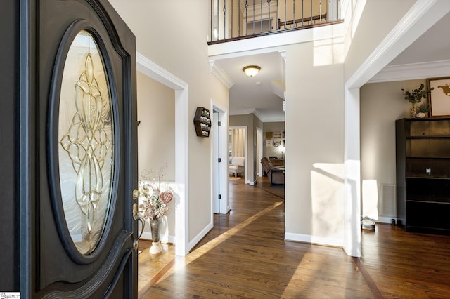 foyer featuring dark hardwood / wood-style flooring, a towering ceiling, and ornamental molding