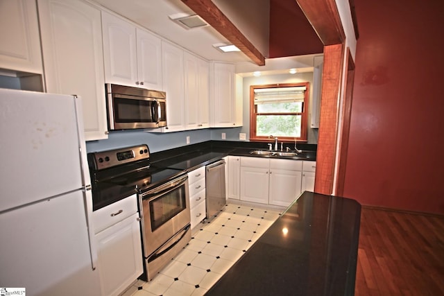 kitchen featuring beamed ceiling, sink, white cabinetry, and stainless steel appliances