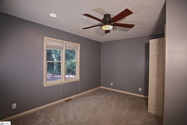 spare room featuring dark carpet and ceiling fan