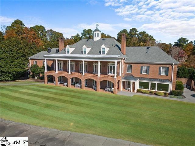 back of house with a lawn and a balcony