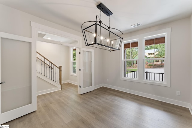 unfurnished dining area featuring light hardwood / wood-style floors, a chandelier, and a wealth of natural light