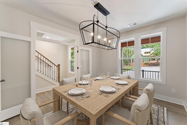 dining area with hardwood / wood-style floors and a notable chandelier
