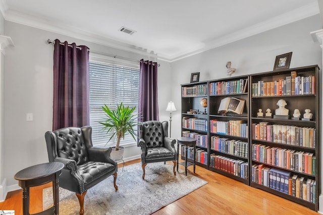 living area with wood-type flooring and crown molding