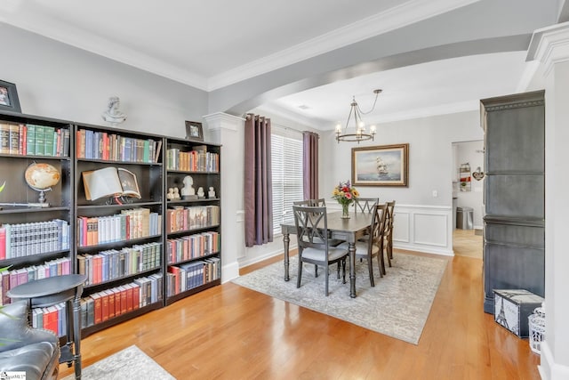 dining space with a notable chandelier, wood-type flooring, and ornamental molding