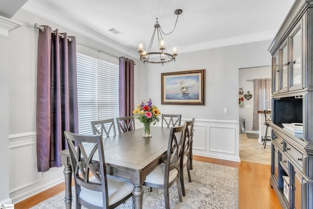 dining room featuring light hardwood / wood-style flooring, ornamental molding, and an inviting chandelier