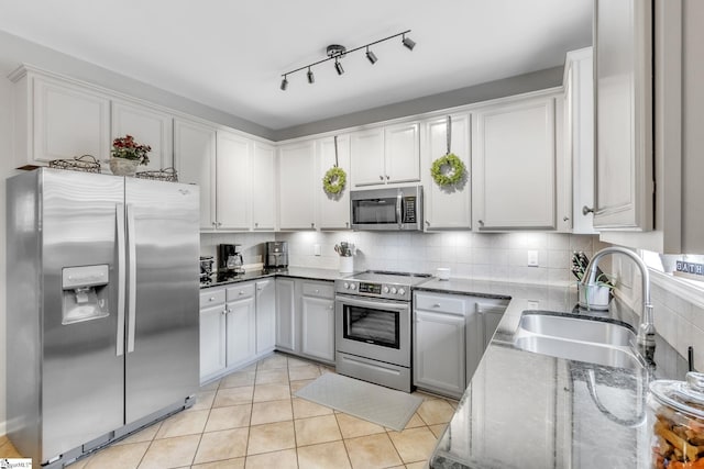 kitchen with white cabinetry, sink, stainless steel appliances, light stone counters, and light tile patterned floors