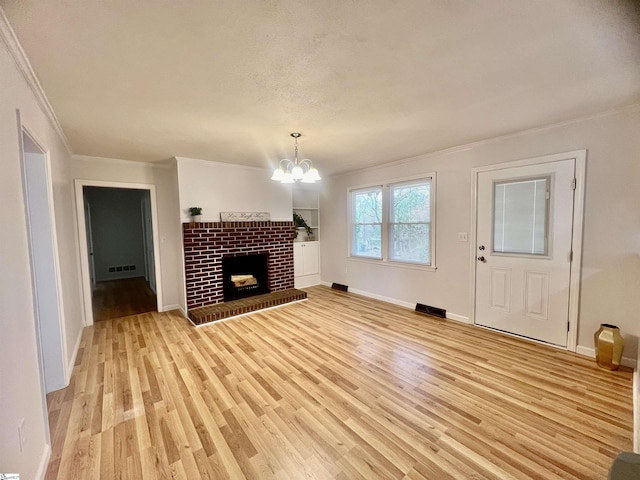 unfurnished living room featuring crown molding, light wood-type flooring, a fireplace, and an inviting chandelier