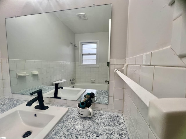 bathroom with tile patterned floors, sink, a bath, and tile walls