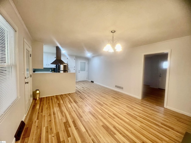 unfurnished living room featuring light hardwood / wood-style flooring, ornamental molding, and an inviting chandelier