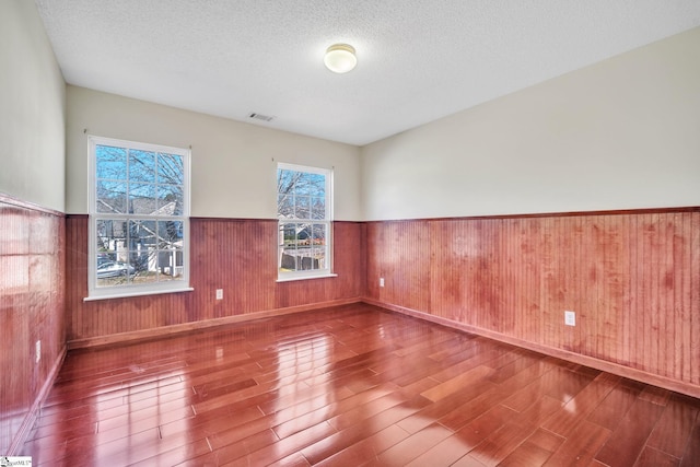 spare room featuring hardwood / wood-style floors and a textured ceiling