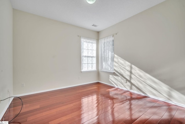 spare room featuring wood-type flooring and a textured ceiling