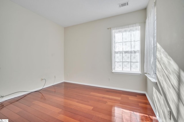 spare room with a wealth of natural light and wood-type flooring