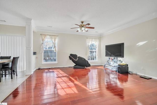 living area featuring a healthy amount of sunlight, crown molding, and wood finished floors