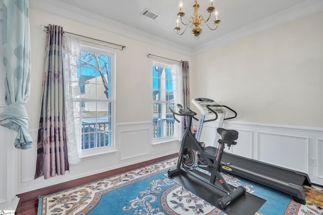 workout room featuring hardwood / wood-style flooring, ornamental molding, and a chandelier