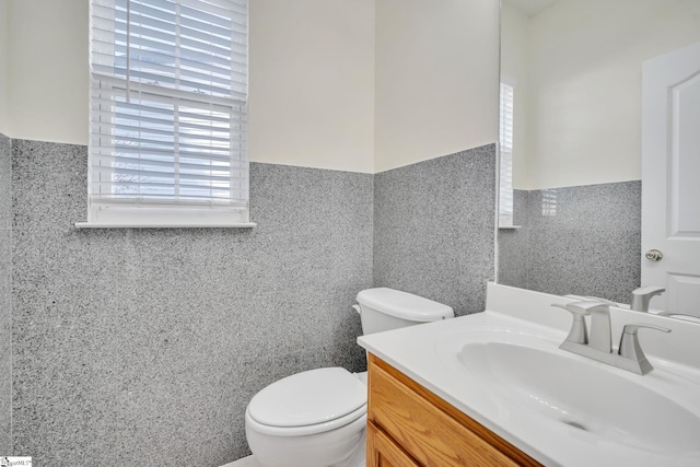 bathroom featuring vanity, tile walls, and toilet