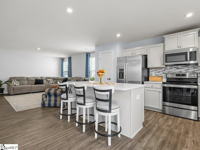 kitchen with stainless steel appliances, a kitchen island, tasteful backsplash, a breakfast bar area, and white cabinets