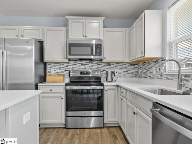 kitchen featuring decorative backsplash, white cabinetry, sink, and appliances with stainless steel finishes