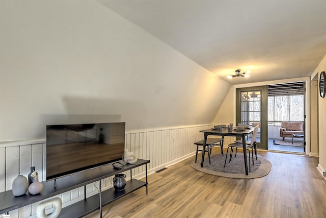 dining room featuring wood-type flooring and vaulted ceiling