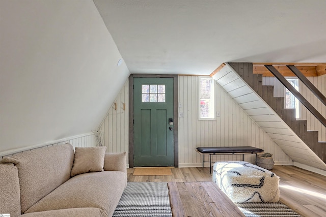 foyer with wooden walls, light hardwood / wood-style flooring, and vaulted ceiling