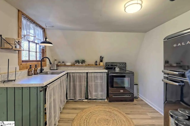 kitchen featuring sink, hanging light fixtures, green cabinetry, light hardwood / wood-style flooring, and black / electric stove