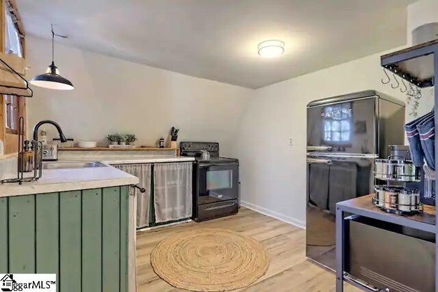 kitchen with black appliances, green cabinets, sink, light wood-type flooring, and decorative light fixtures