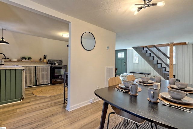 dining space featuring a textured ceiling, light hardwood / wood-style floors, and sink