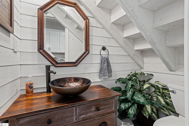 bathroom featuring vanity, toilet, and wood walls