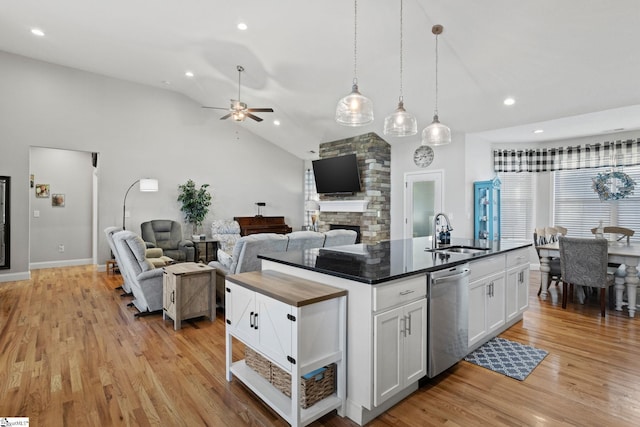 kitchen with white cabinetry, dishwasher, sink, lofted ceiling, and a center island with sink