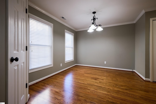 spare room with a chandelier, ornamental molding, and dark wood-type flooring