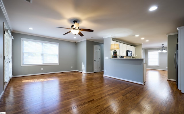 unfurnished living room featuring dark wood-type flooring, ceiling fan with notable chandelier, and ornamental molding