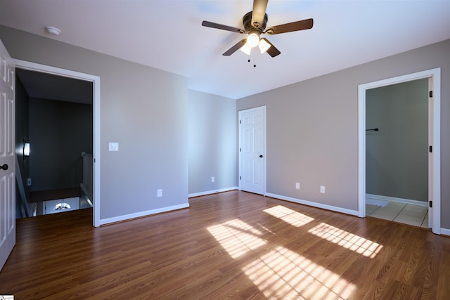 unfurnished bedroom featuring ceiling fan, a closet, and dark wood-type flooring