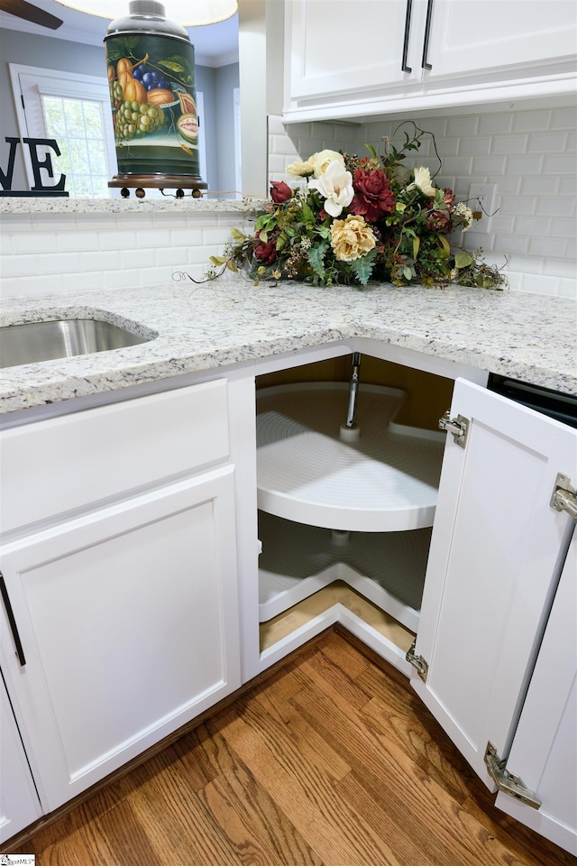 room details with light stone countertops, tasteful backsplash, white cabinetry, and hardwood / wood-style flooring