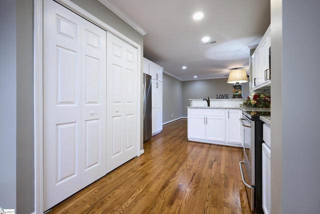 kitchen featuring light stone countertops, white cabinetry, stainless steel appliances, dark hardwood / wood-style flooring, and kitchen peninsula