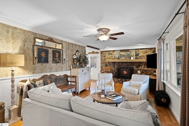 living room with a wood stove, crown molding, light hardwood / wood-style flooring, and ceiling fan