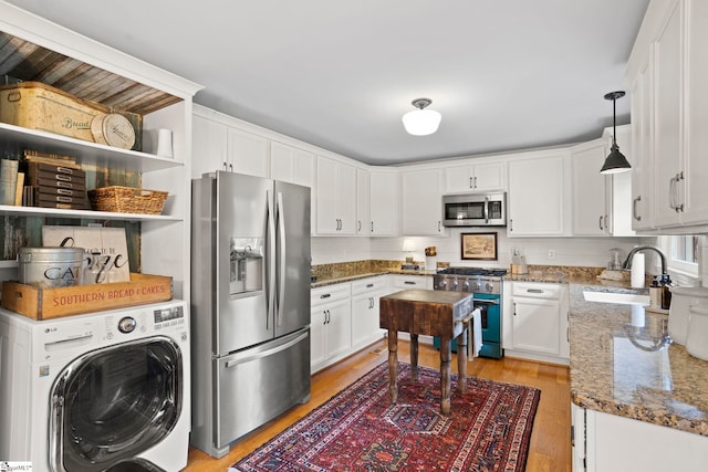 kitchen with white cabinetry, sink, pendant lighting, washer / dryer, and appliances with stainless steel finishes