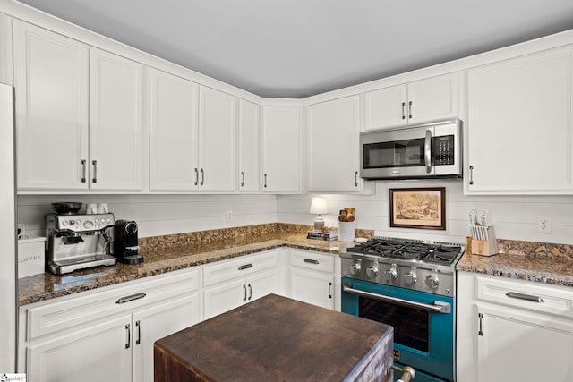 kitchen featuring decorative backsplash, white cabinetry, dark stone counters, and appliances with stainless steel finishes