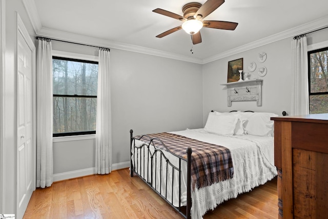 bedroom featuring multiple windows, light hardwood / wood-style floors, ceiling fan, and crown molding