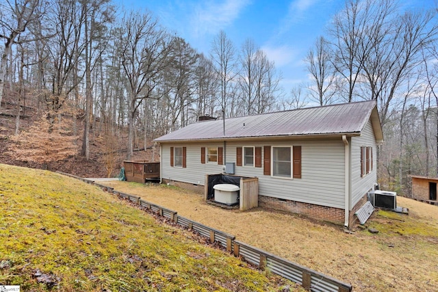 exterior space featuring a front yard, central air condition unit, and a wooden deck